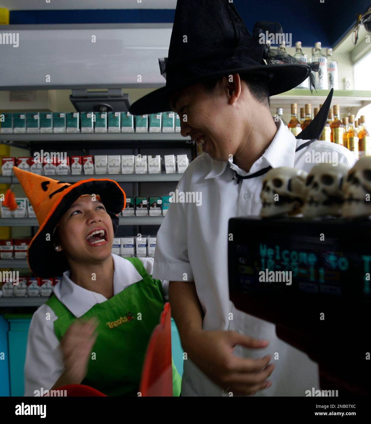 Two convenient store attendants joke with each other as they wear their