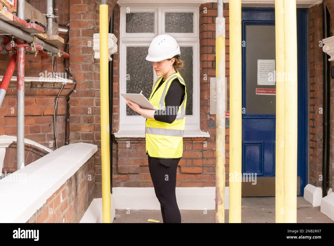 A serious female civil engineer carrying out an inspection and supervising a construction site building, hard hat and yellow personal protective equip Stock Photo