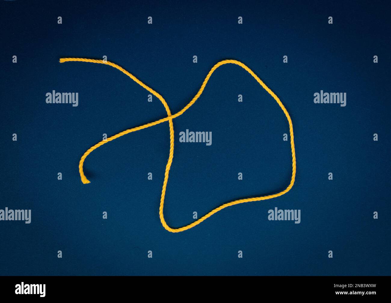 A bright colored thread located on a dark colored background. A single bright thread Stock Photo