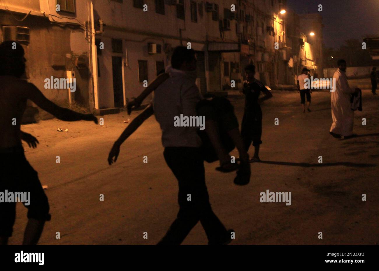 A Bahraini man carries a youth overcome by tear gas fired by riot ...