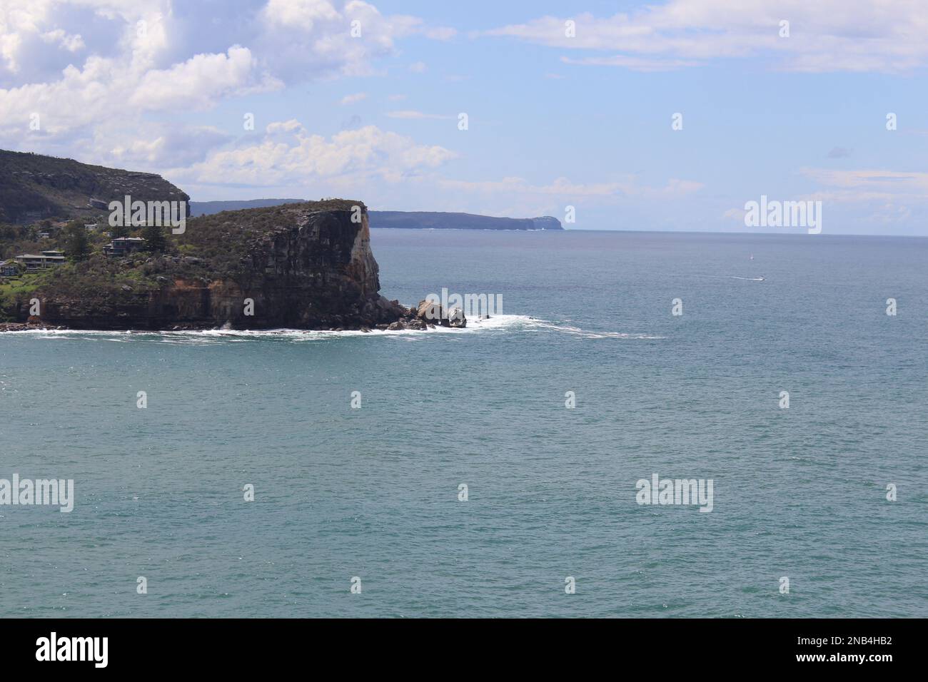 A rocky cliff with a sea view and blue cloudy sky Stock Photo - Alamy