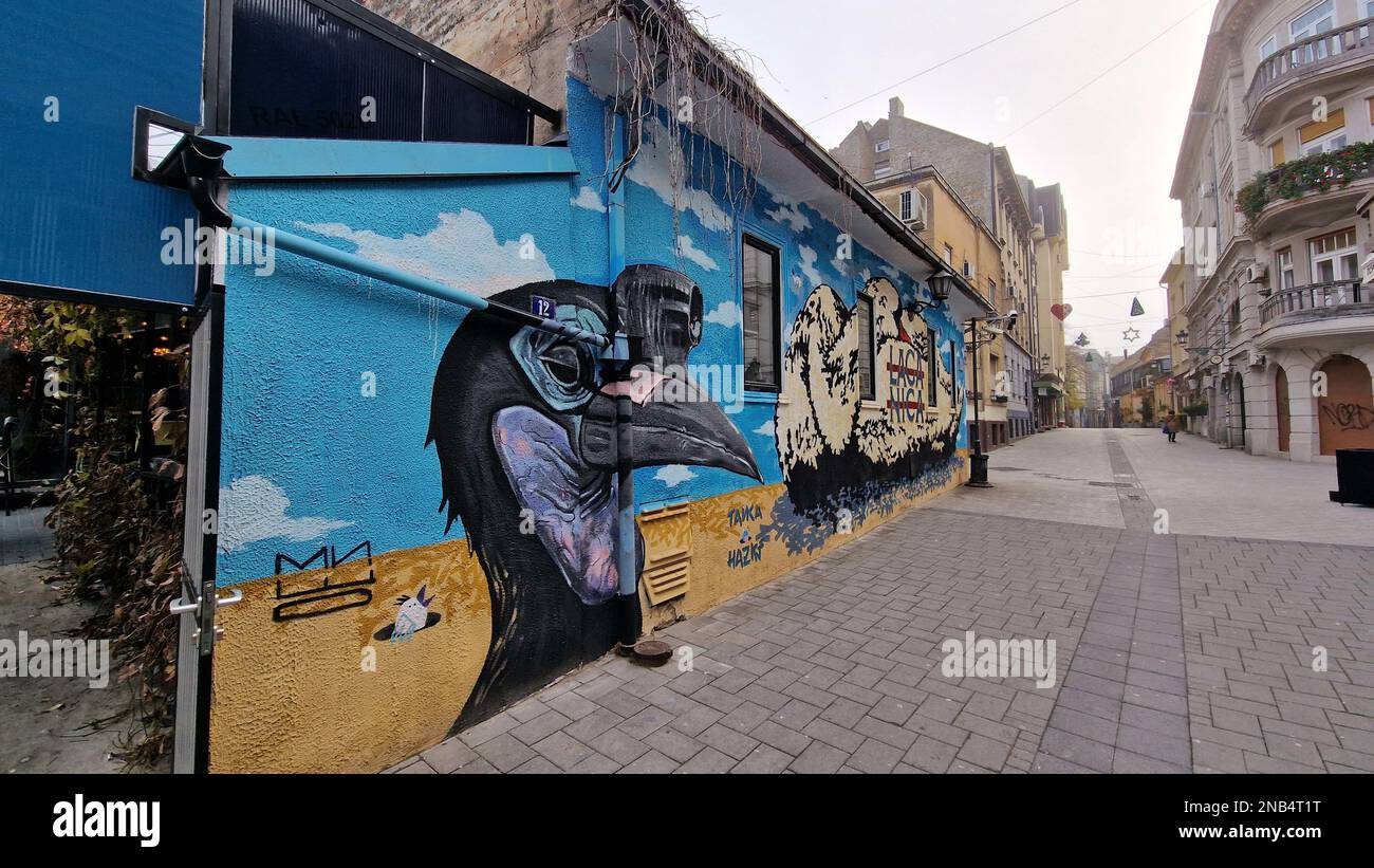 The colorful mural painted on the side of a building on the sidewalk ...