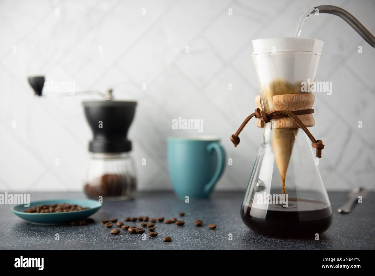 Preparing Pour-Over coffee in glass container on clean stone countertop with white marble backsplash Stock Photo