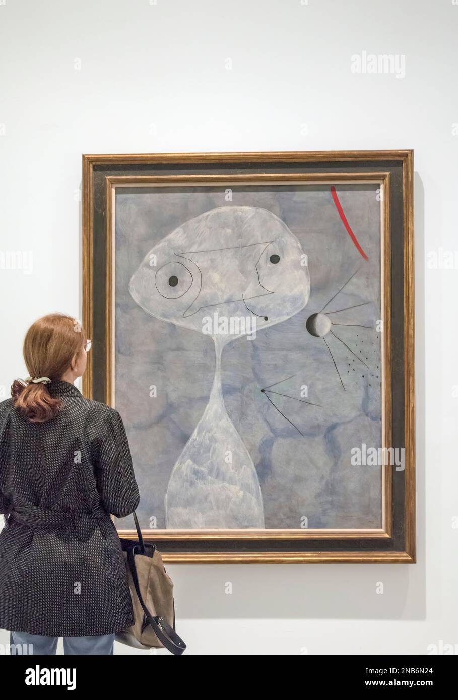 A woman looks at a Joan Miro painting entitled Man With A Pipe (1925) in the Reina Sofia Museum in Madrid, Spain Stock Photo