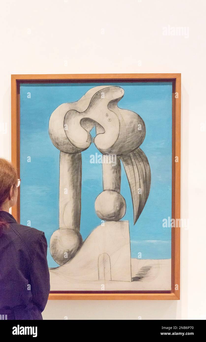 A woman looks at a Pablo Picasso painting entitled Figures by the Sea I (1932) in the Reina Sofia Museum in Madrid, Spain with copy space Stock Photo