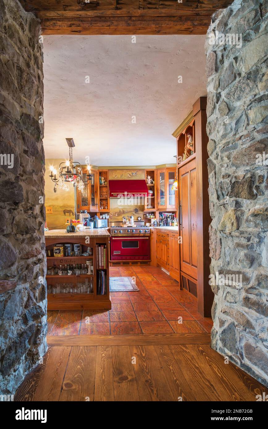 View of kitchen with pine wood cabinets, stone and inlaid ceramic tile top  island framed by fieldstone walls and a timber beam inside old 1826 home  Stock Photo - Alamy, image size:867x1390