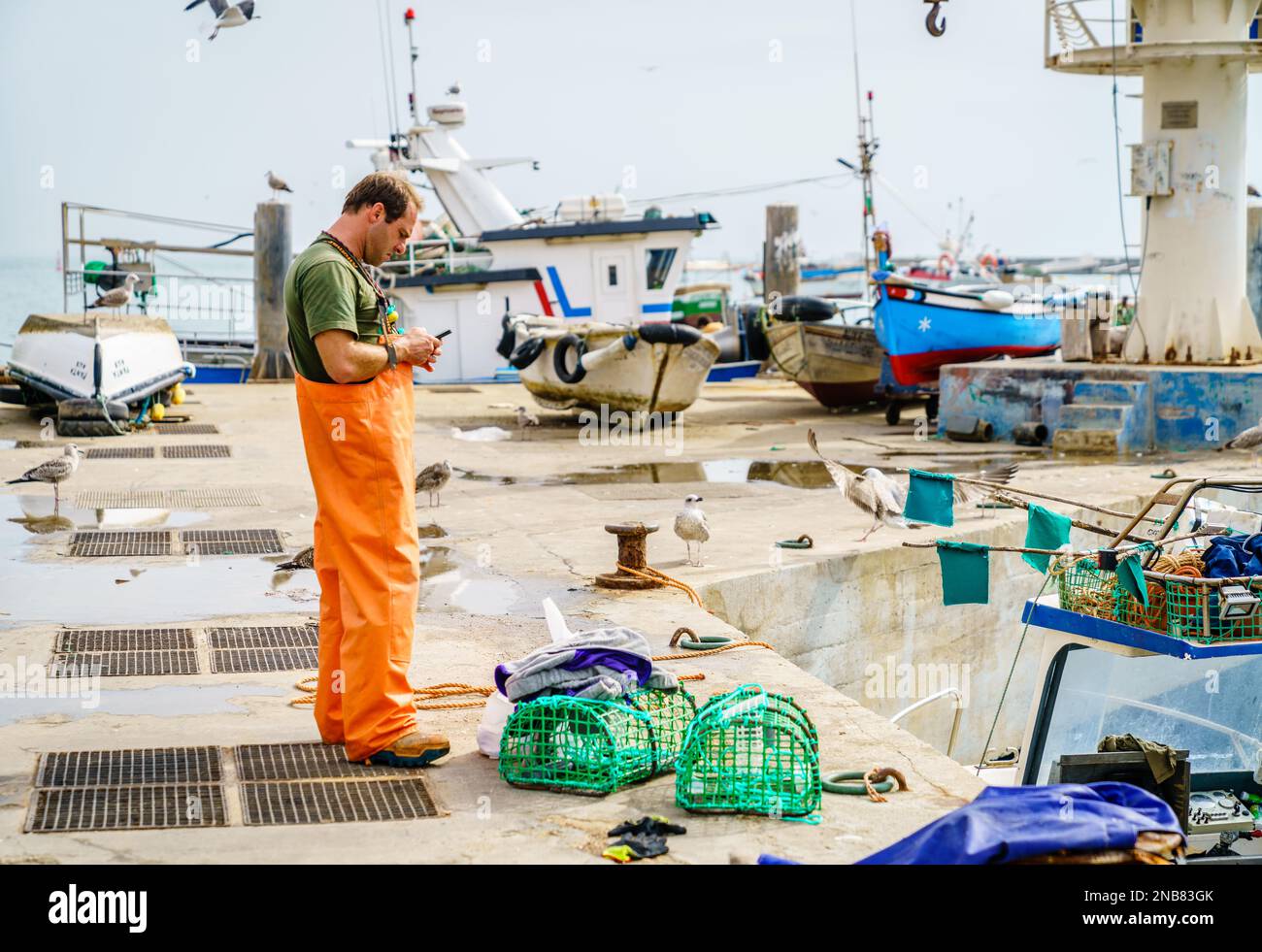 Cascais, Portugal, October 27, 2016: A fisherman is looking at his phone after coming shore in Cascais, Portugal Stock Photo