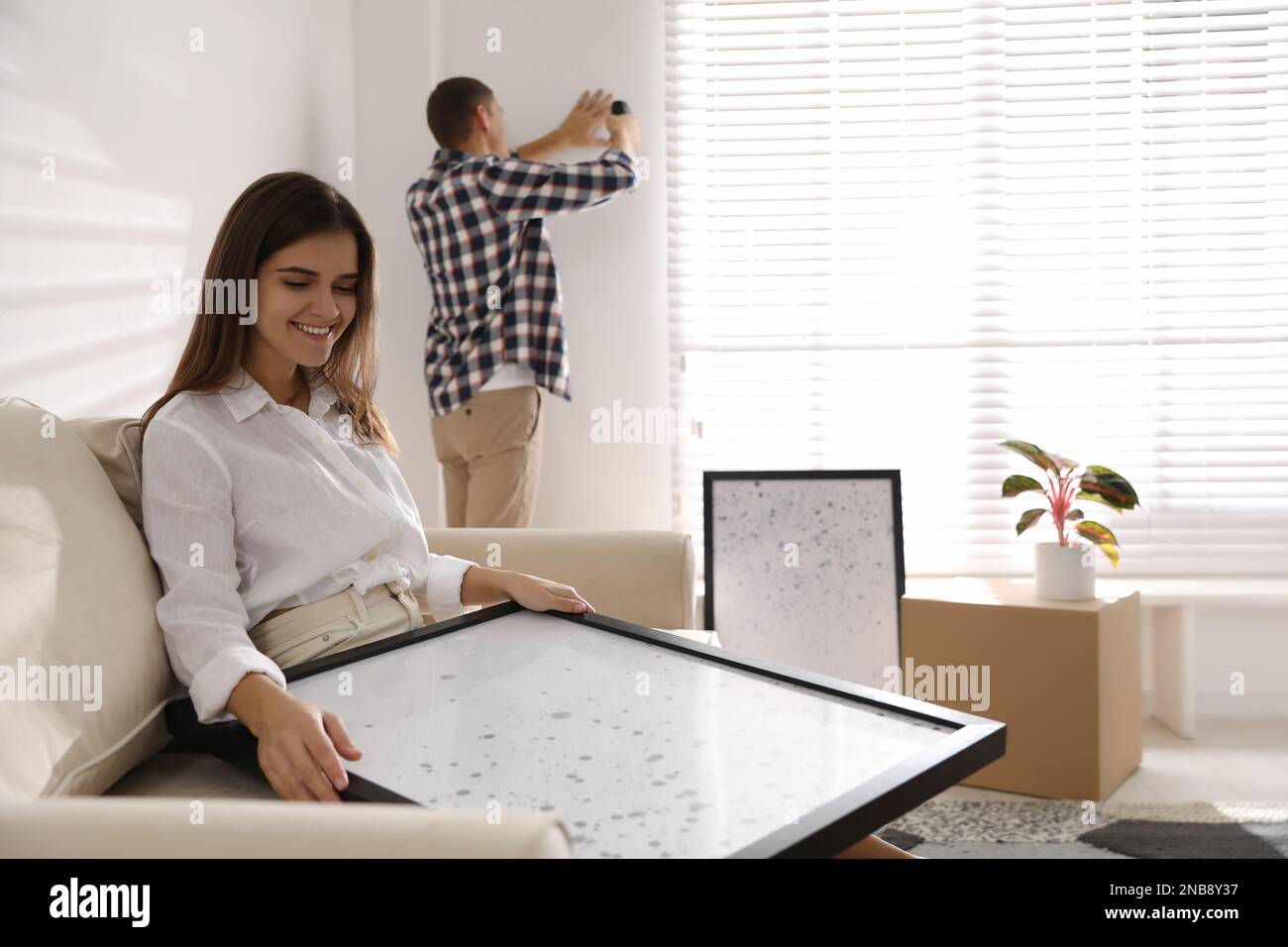 Happy couple decorating room with pictures together. Interior design ...