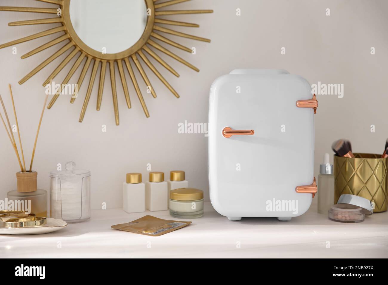 Cosmetics refrigerator and skin care products on white vanity table