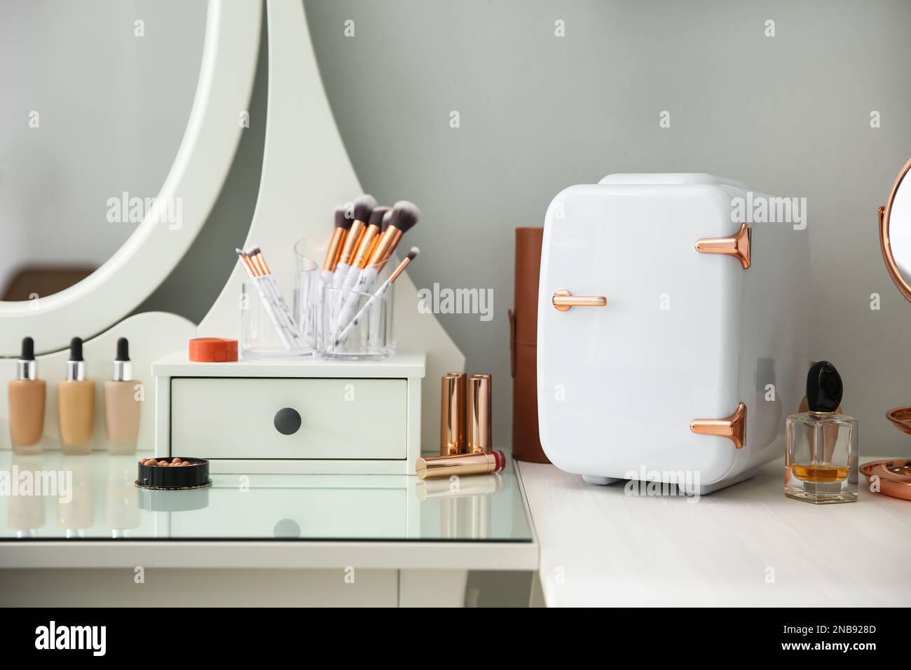 Cosmetics refrigerator and skin care products on white vanity table