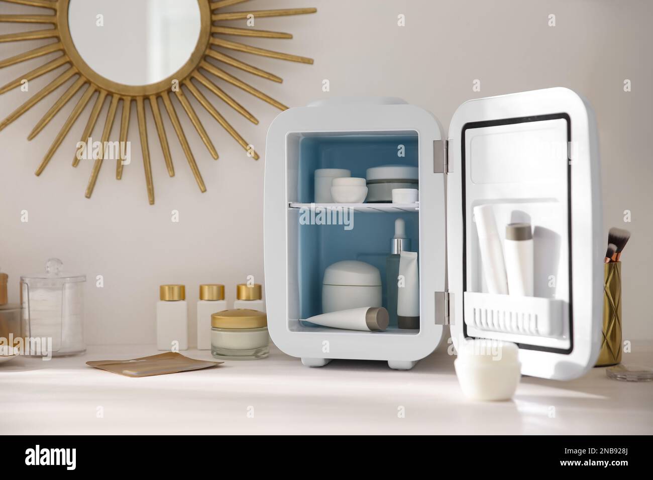 Cosmetics refrigerator and skin care products on white vanity table