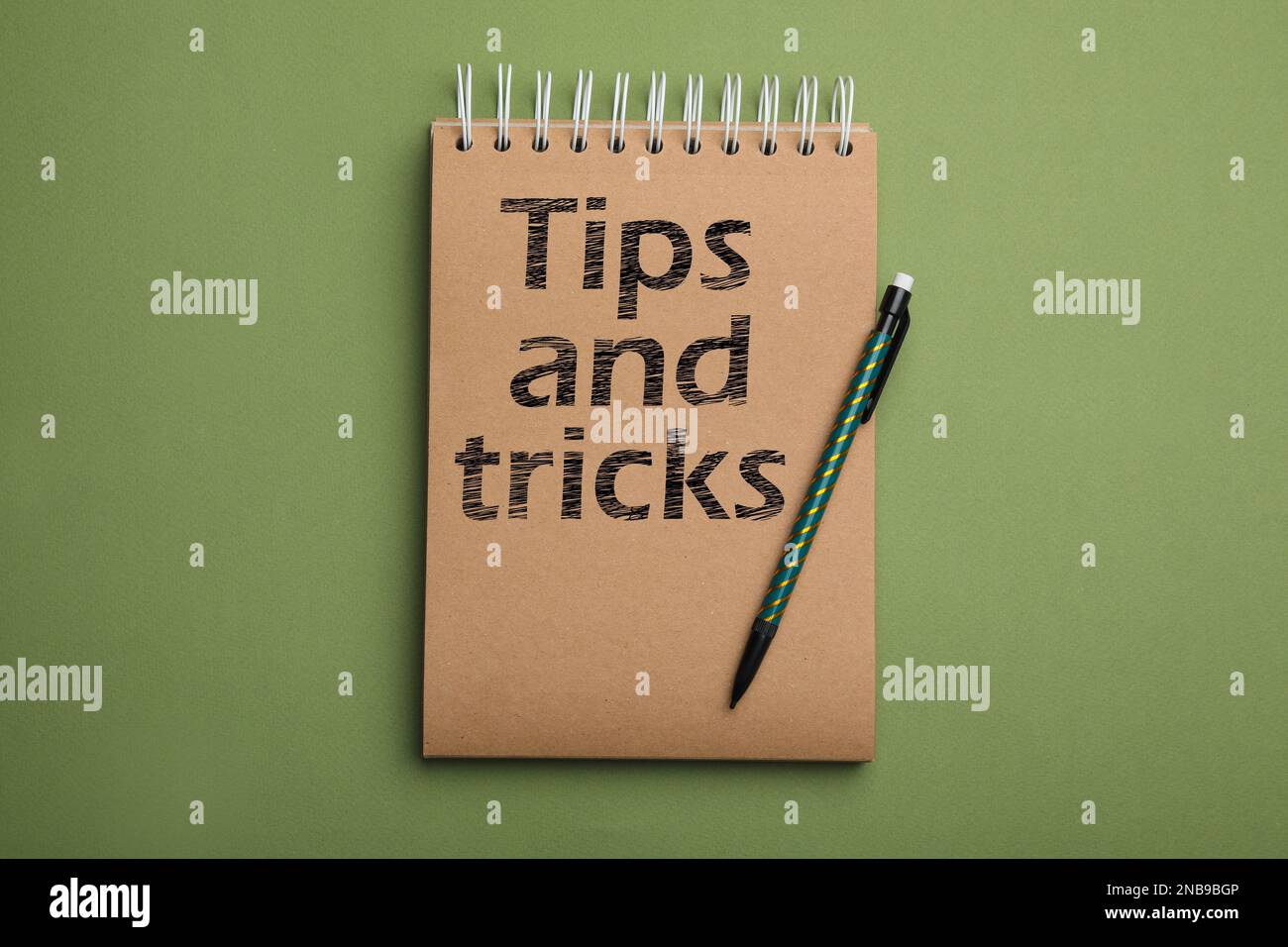 Notebook with text tips and tricks on green background top view stock
