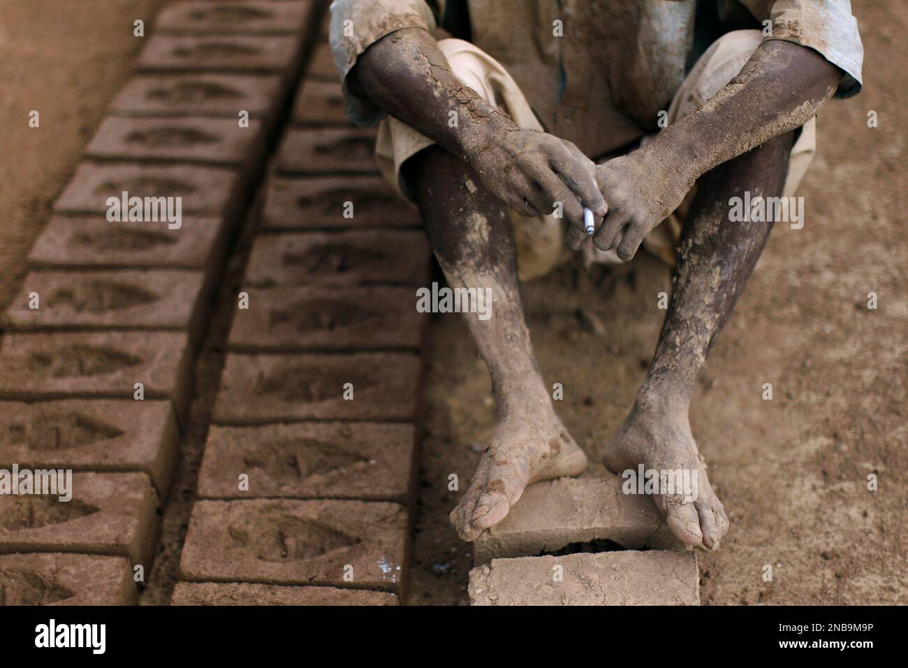 Pakistani brick factory worker, Altaf Manzoor, 36, smokes a cigarette ...