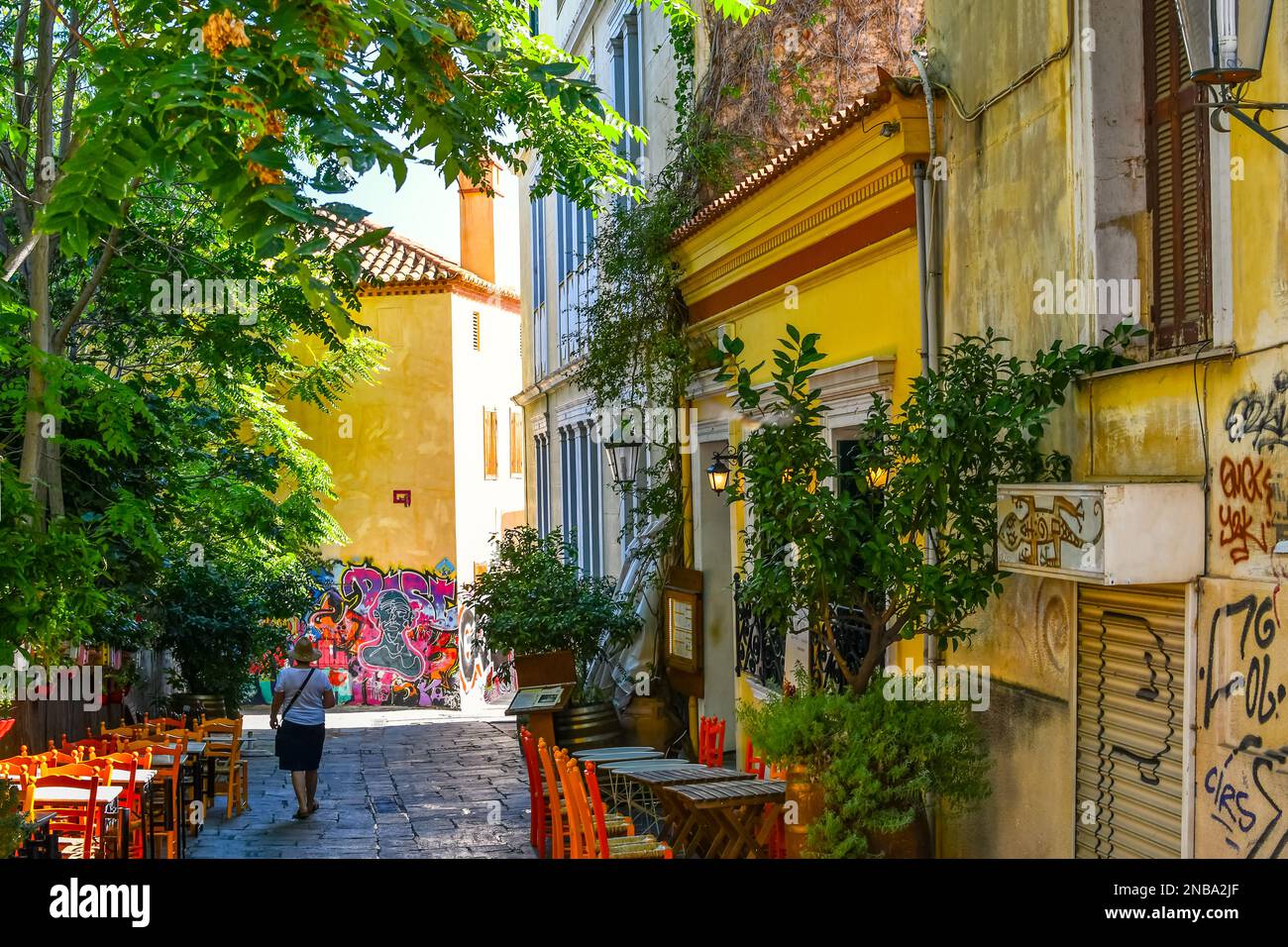 A colorful hillside alley in the Plaka district of Athens, Greece, with cafes, terraces, tables and chairs, at the base of the ancient Acropolis. Stock Photo