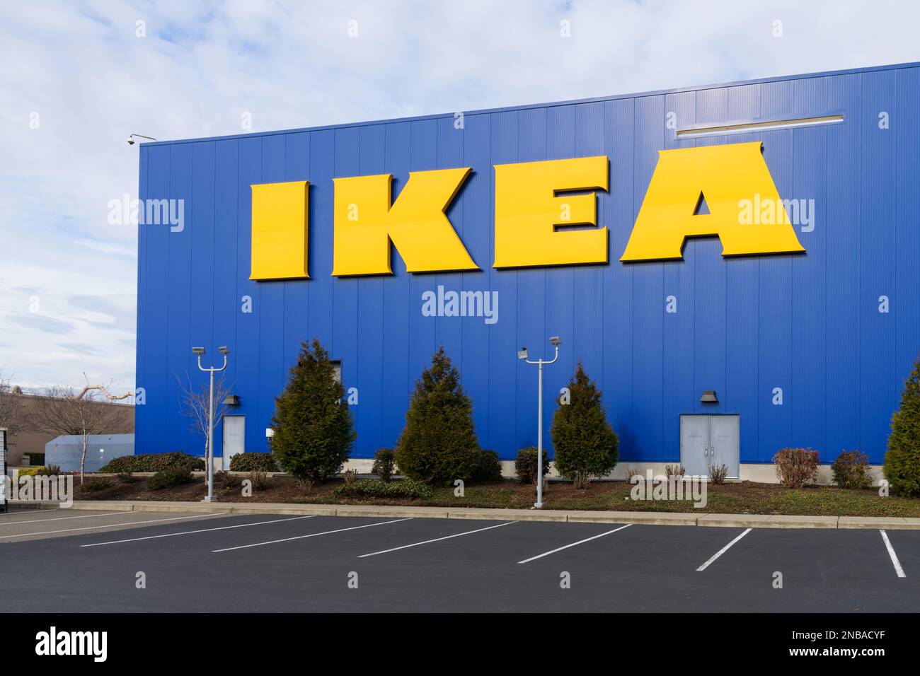 Renton, WA, USA - February 12, 2023; Yellow IKEA store name on blue wall of warehouse with parking Stock Photo