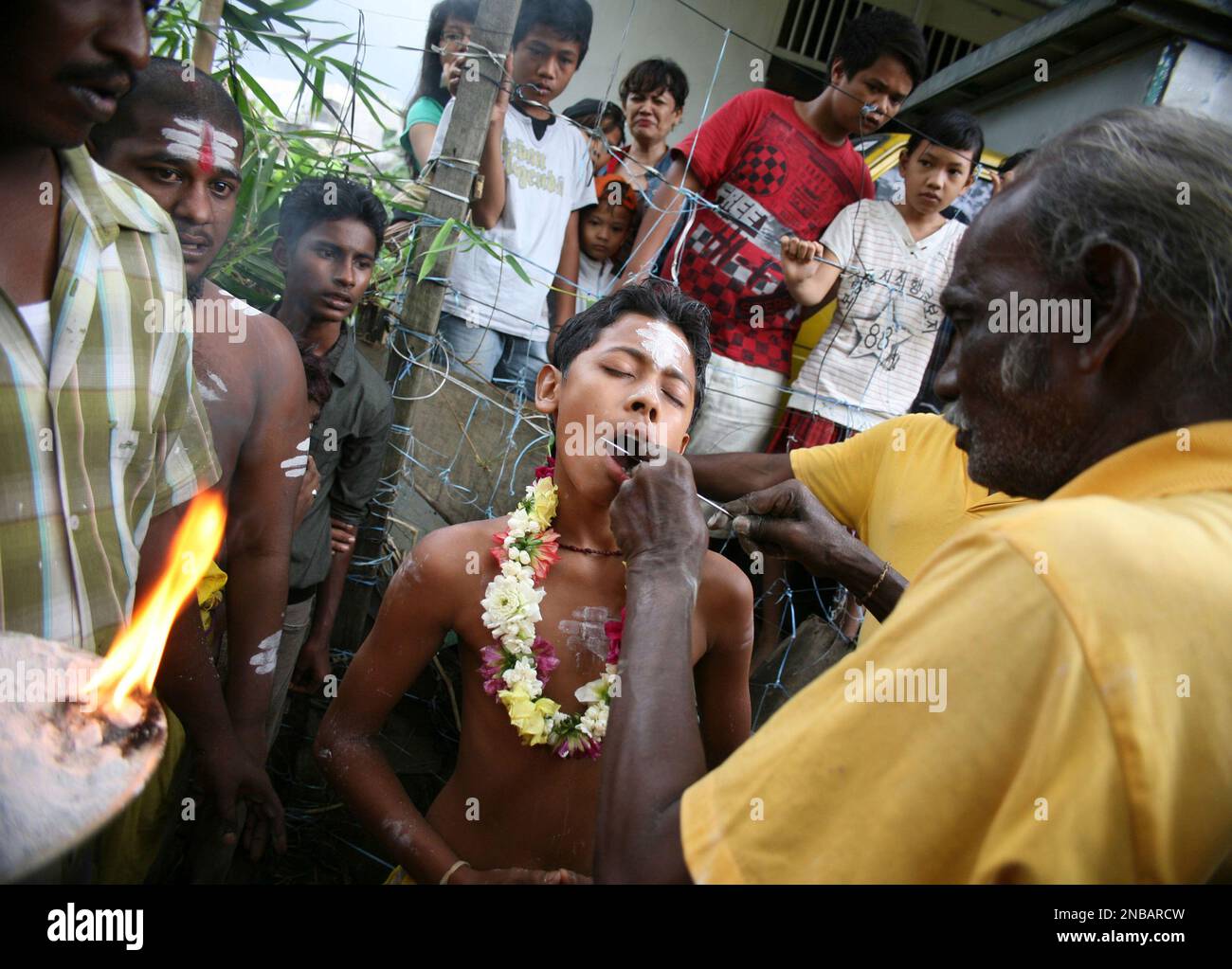 An ethnic Tamil priest pierces the cheks of a youth during the Hindu ...