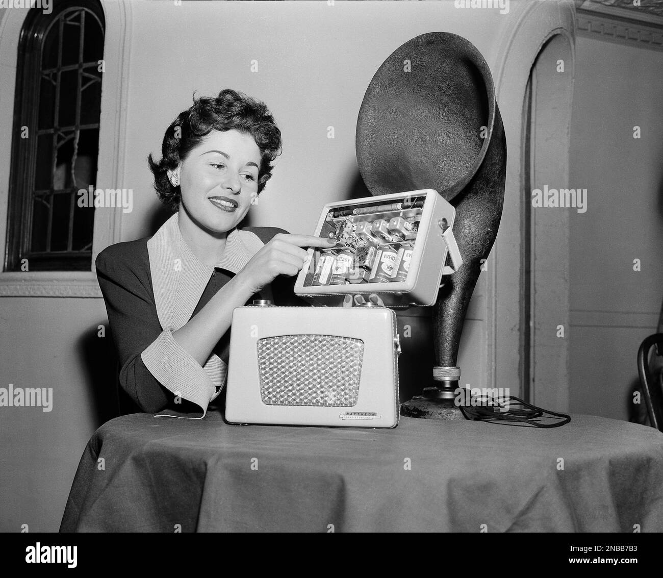 Shirley Schaefer points to the chassis of a tubeless portable radio being  at the mid-winter furniture market in Chicago, Jan. 4, 1955. Henry F.  Argento, General Manager of the Raytheon Manufacturing Co.,