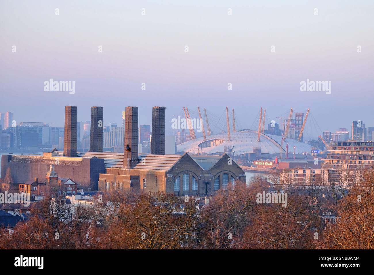 London, UK. 13th February, 2023. A view of the 02 Arena in south-east London from Greenwich Park. Hazy conditions were observed at Greenwich Park during sunset and dusk, as southerly winds are expected to bring Saharan dust deposits to the UK, which will peak between Tuesday and Wednesday. The mineral dust in the atmosphere can turn skies an orange hue, cause 'blood rain' and spectacular sunrises and sunsets. Credit: Eleventh Hour Photography/Alamy Live News Stock Photo