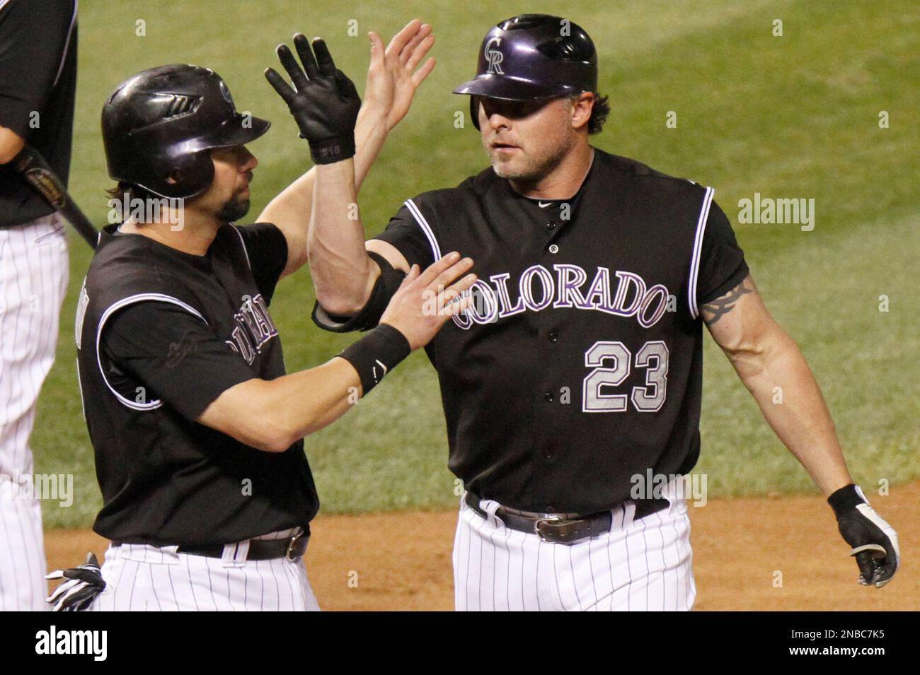 Colorado Rockies' Jason Giambi (23) is congratulated by teammate Todd  Helton (17) after hitting a two-run home run in off of Florida Marlins' Leo  Nunez during the ninth inning of a baseball