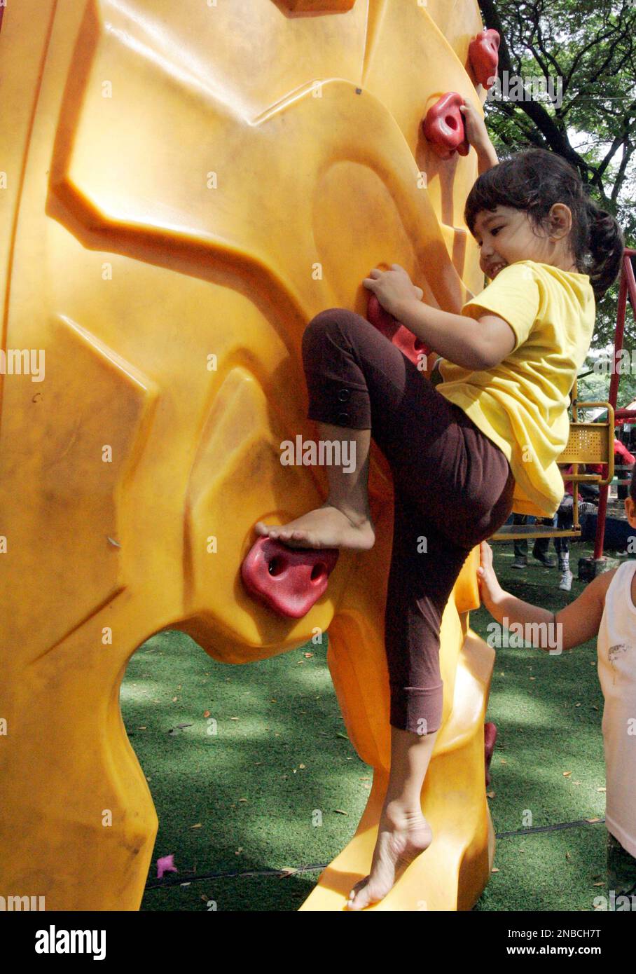A little girl tries wall climbing designed for children in a park