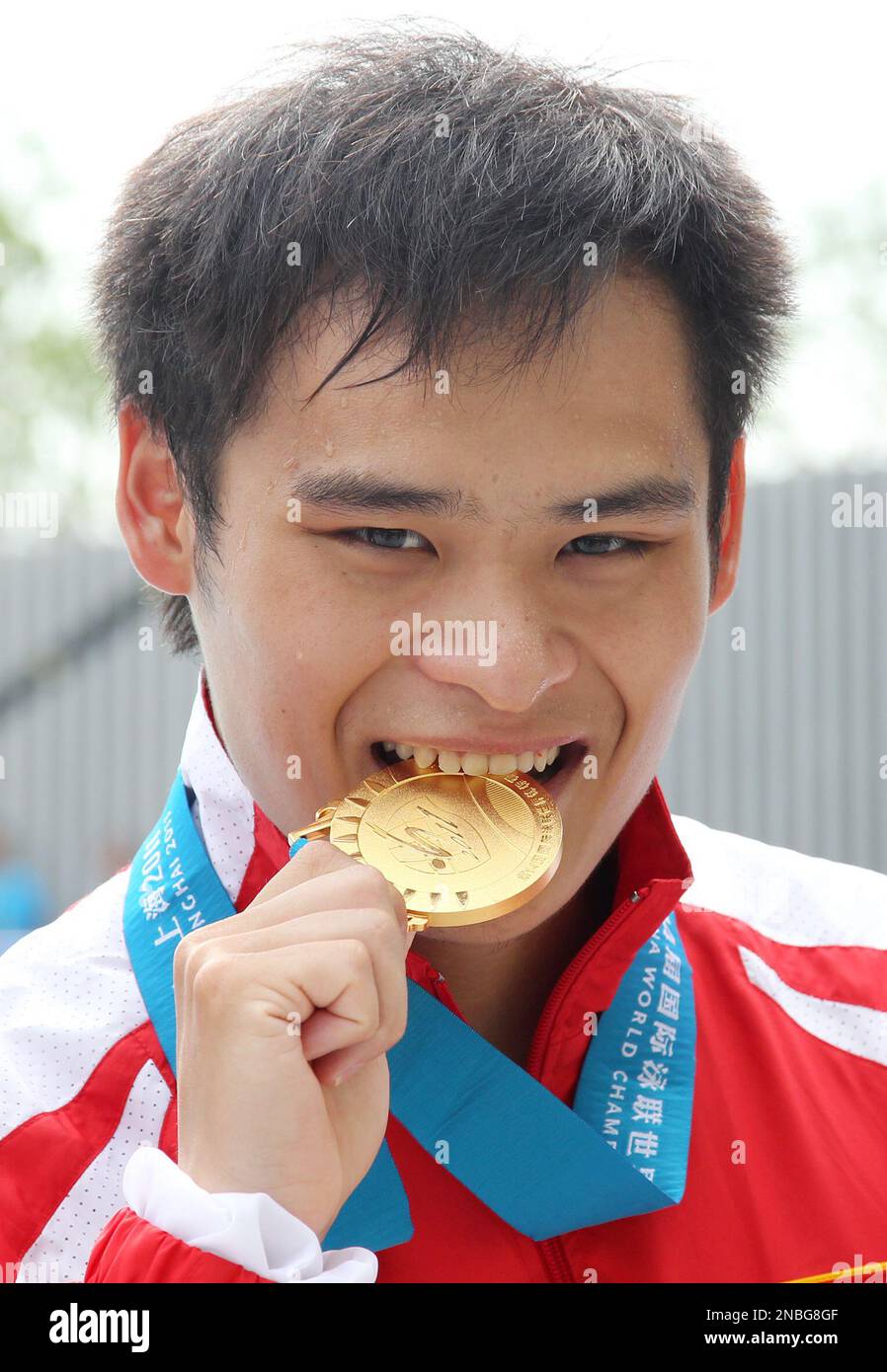 China's Li Shixin bites his gold medal after winning the men's 1meter