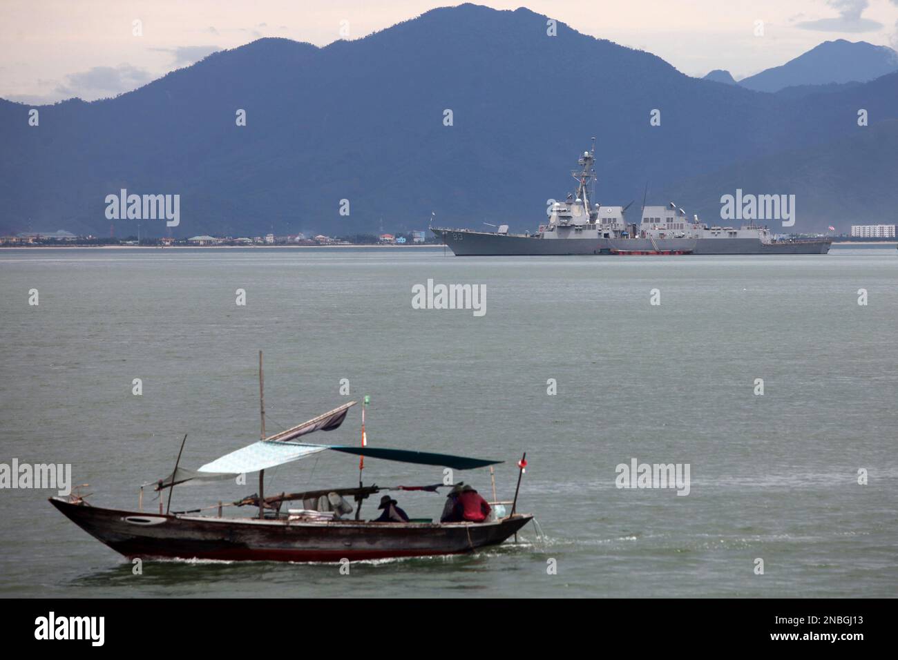 A Vietnamese fisher boat passes near the guided missile destroyer USS ...