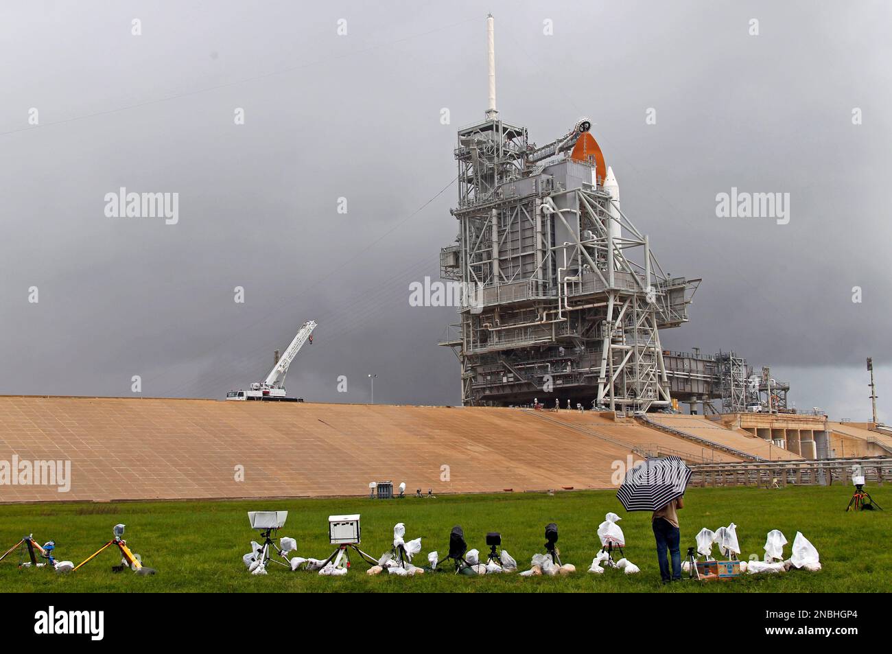 The space shuttle Atlantis sits on the launch pad as a rain cloud ...