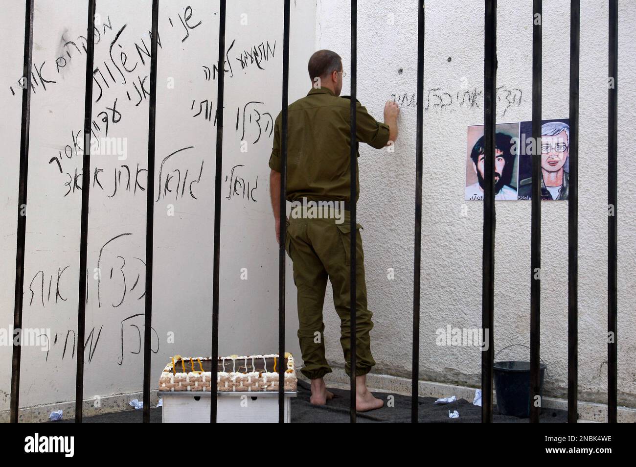 A Palestinian writes on the wall of a mock prison cell as he plays the