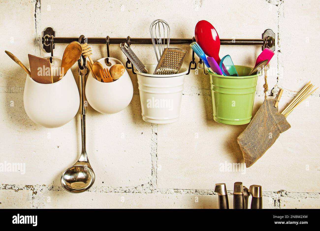 Kitchen utensils.A hanger with multicolored buckets containing various kitchen utensils against