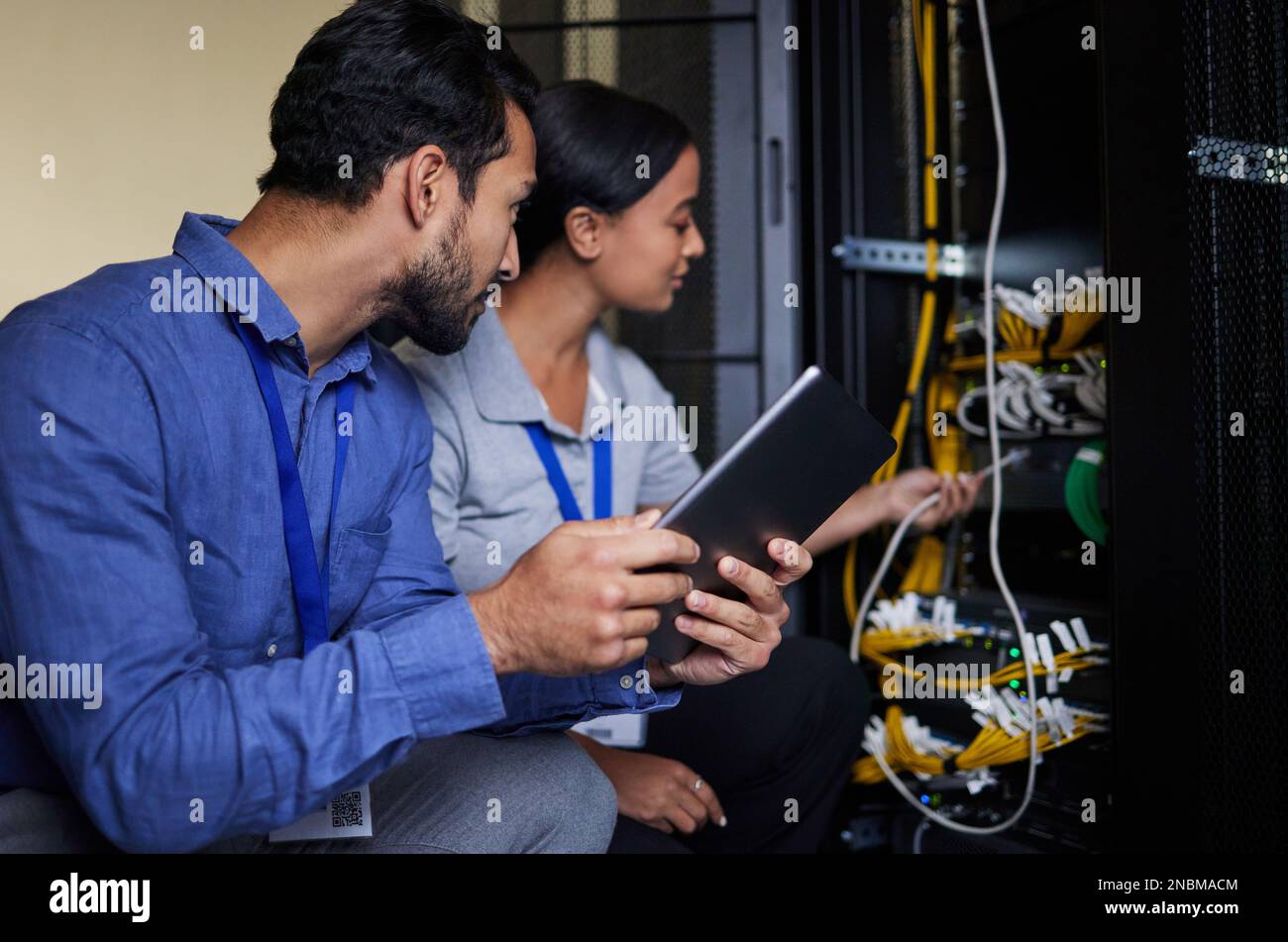 Engineer teamwork, server room and tablet for connection cable, maintenance or software update at night. Cybersecurity wire, programmers or man and Stock Photo
