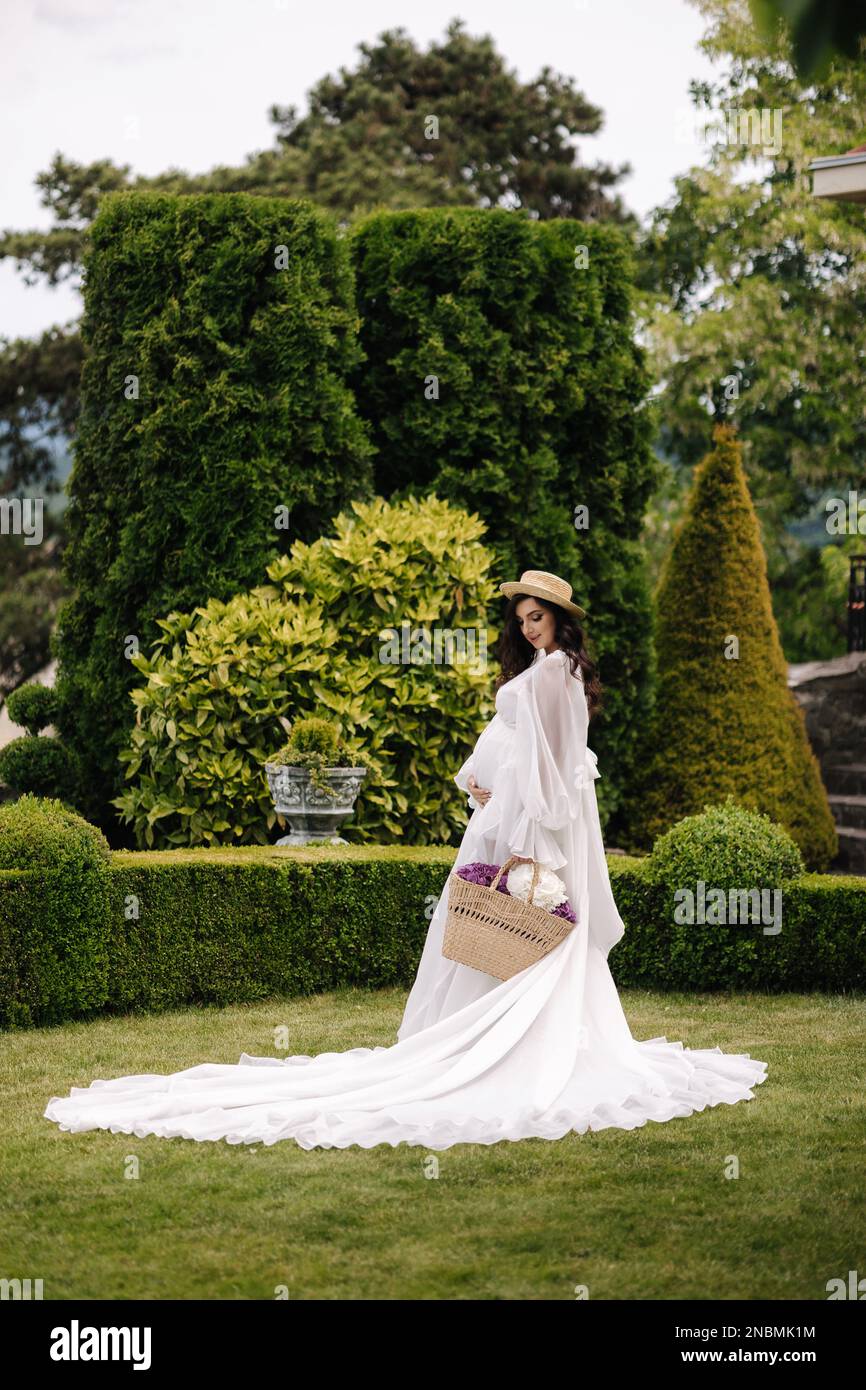 Elegant pregnant woman in beautiful white dress walking outdoors ...