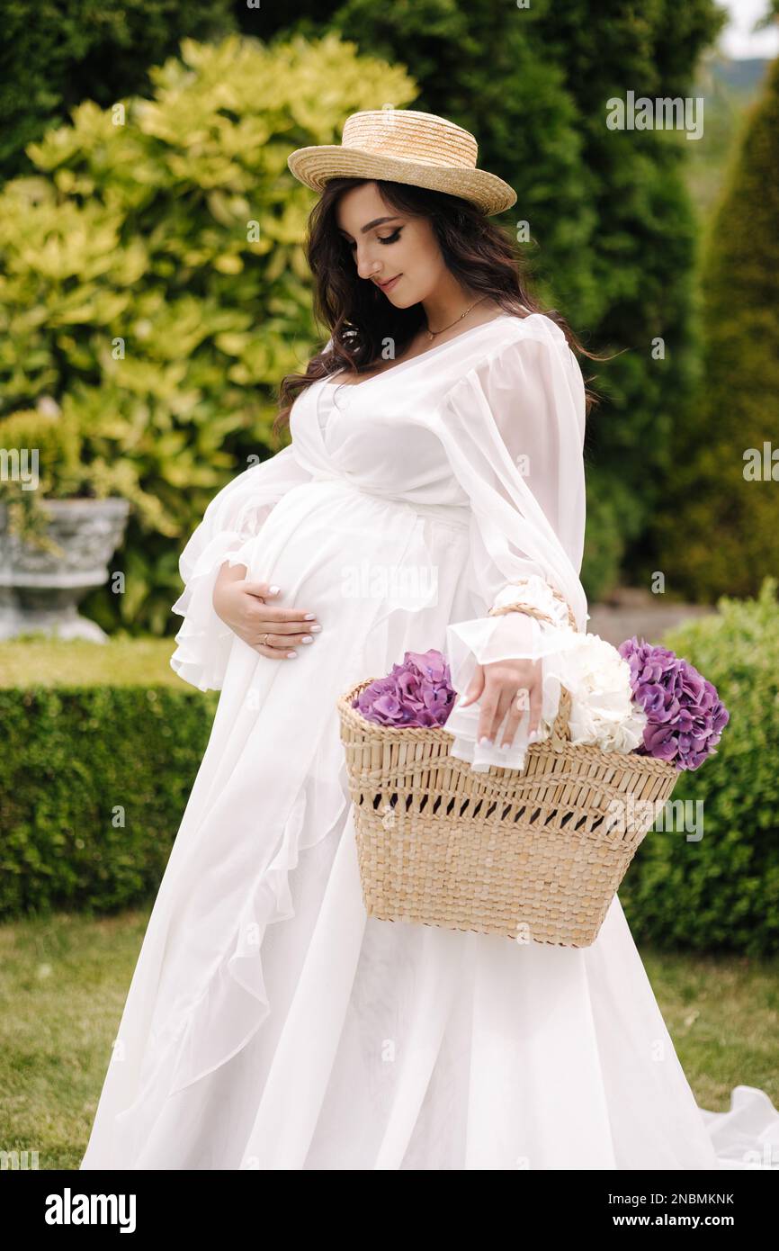 Elegant pregnant woman in beautiful white dress walking outdoors ...
