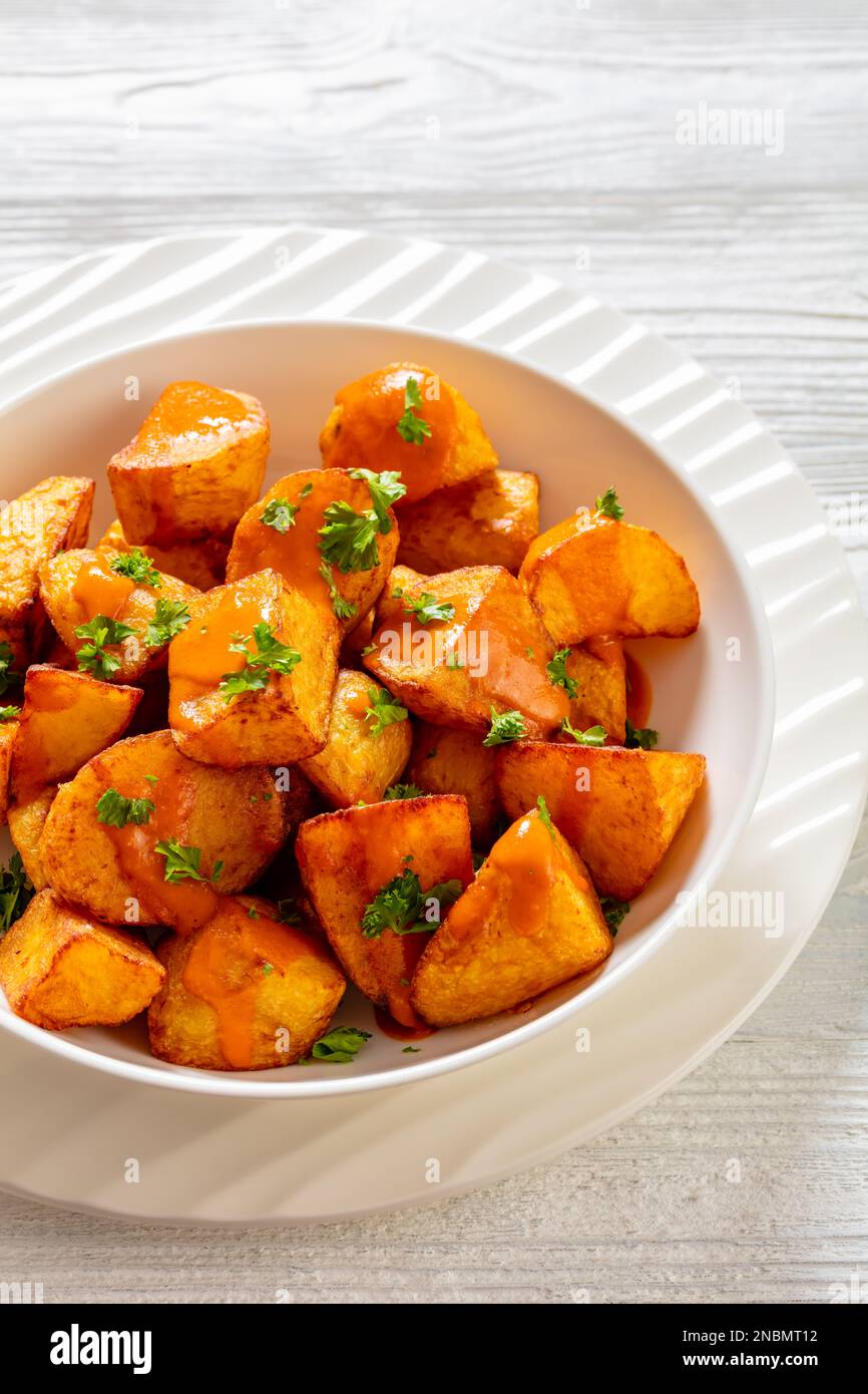 patatas bravas, deep fried potatoes with spicy sauce in white bowl on