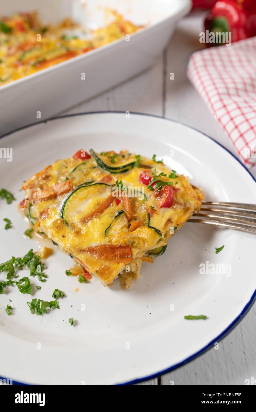 Frittata with zucchini, tomatoes, carrots, onions and bell pepppers on a plate Stock Photo
