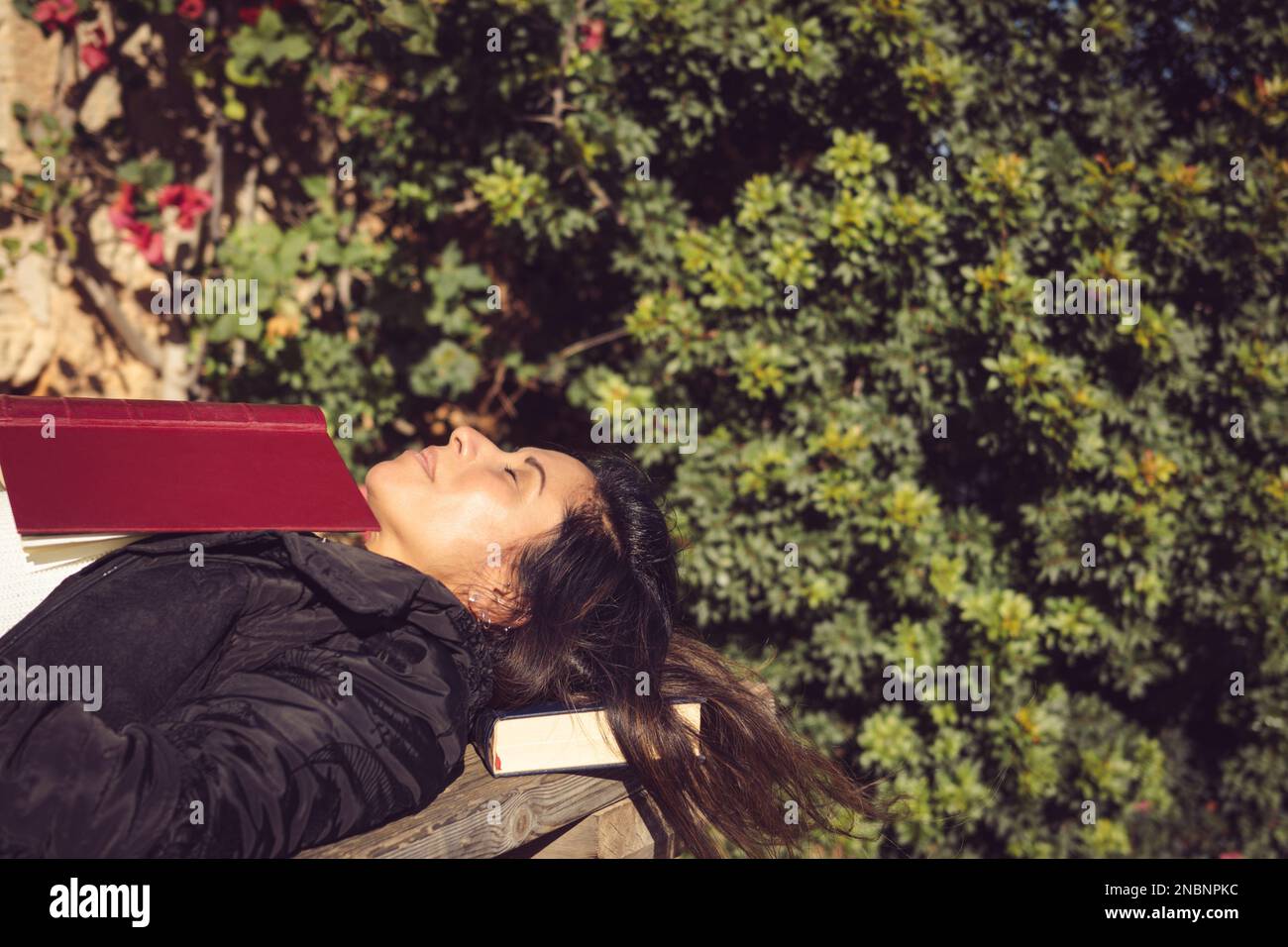 woman lying and sleeping on a wooden table with a book Stock Photo