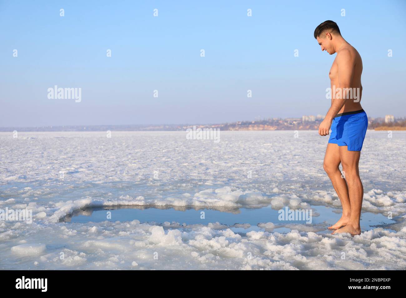 Man near ice hole on winter day. Baptism ritual Stock Photo