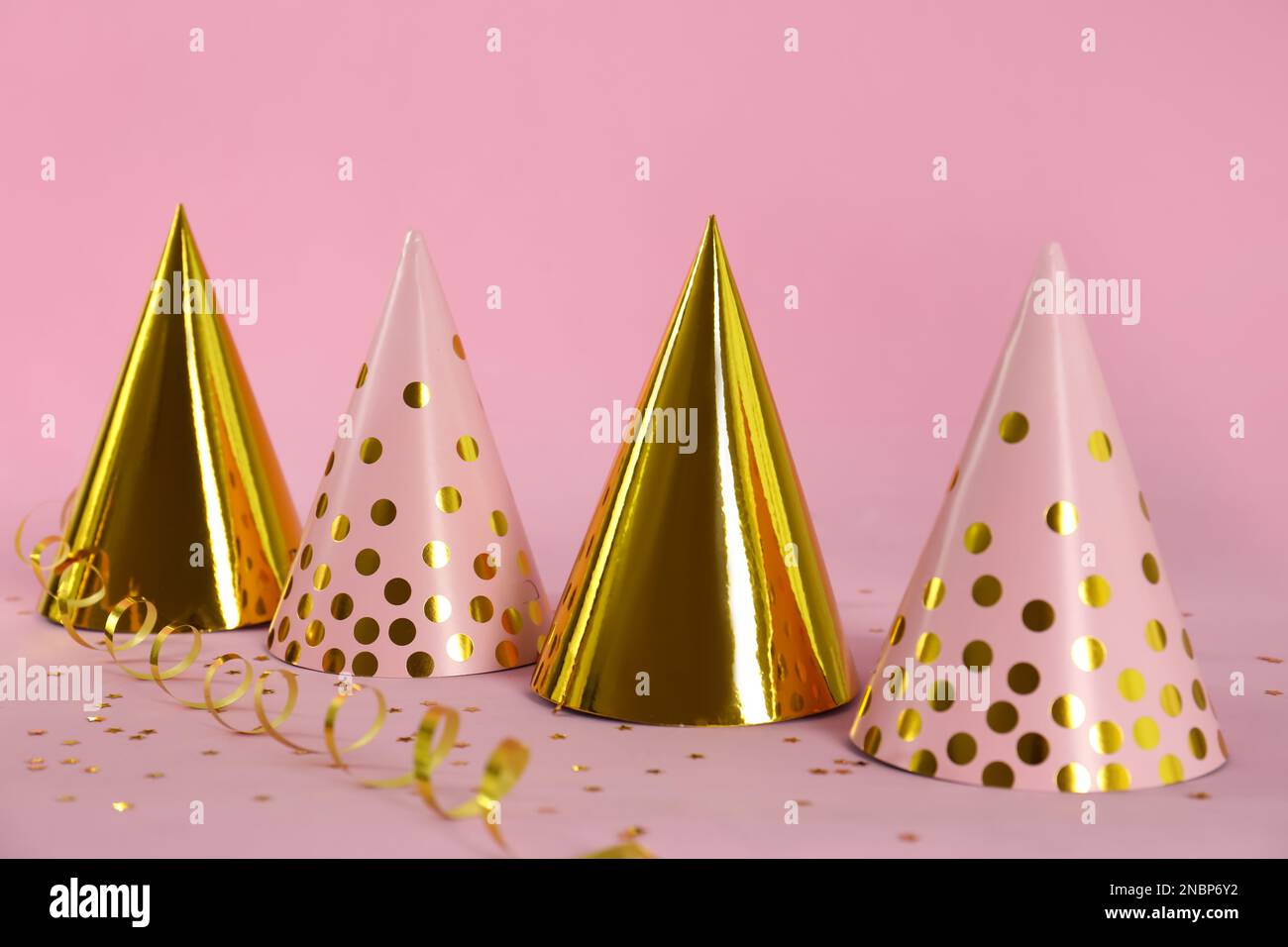 Colorful party hats and confetti on pink background Stock Photo - Alamy