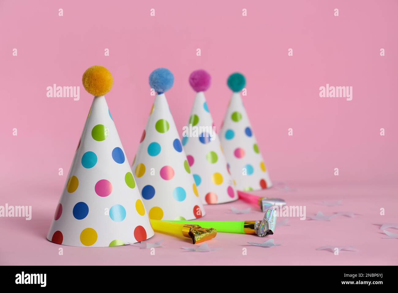 Colorful party hats with fluffy balls and blowers on pink background ...