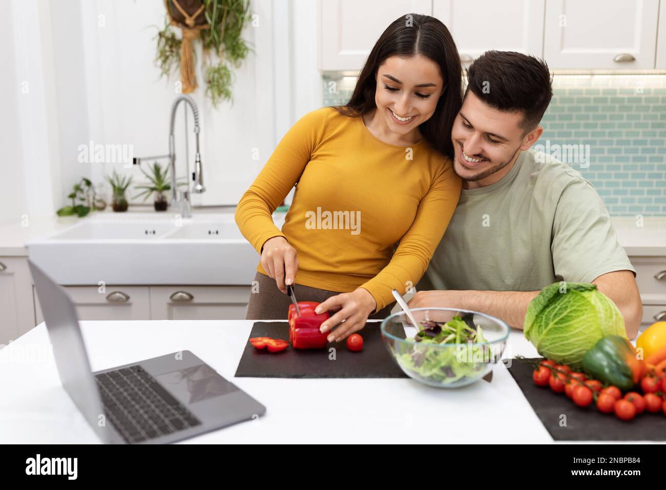 Handsome guy helping his pretty girlfriend making dinner at home Stock Photo