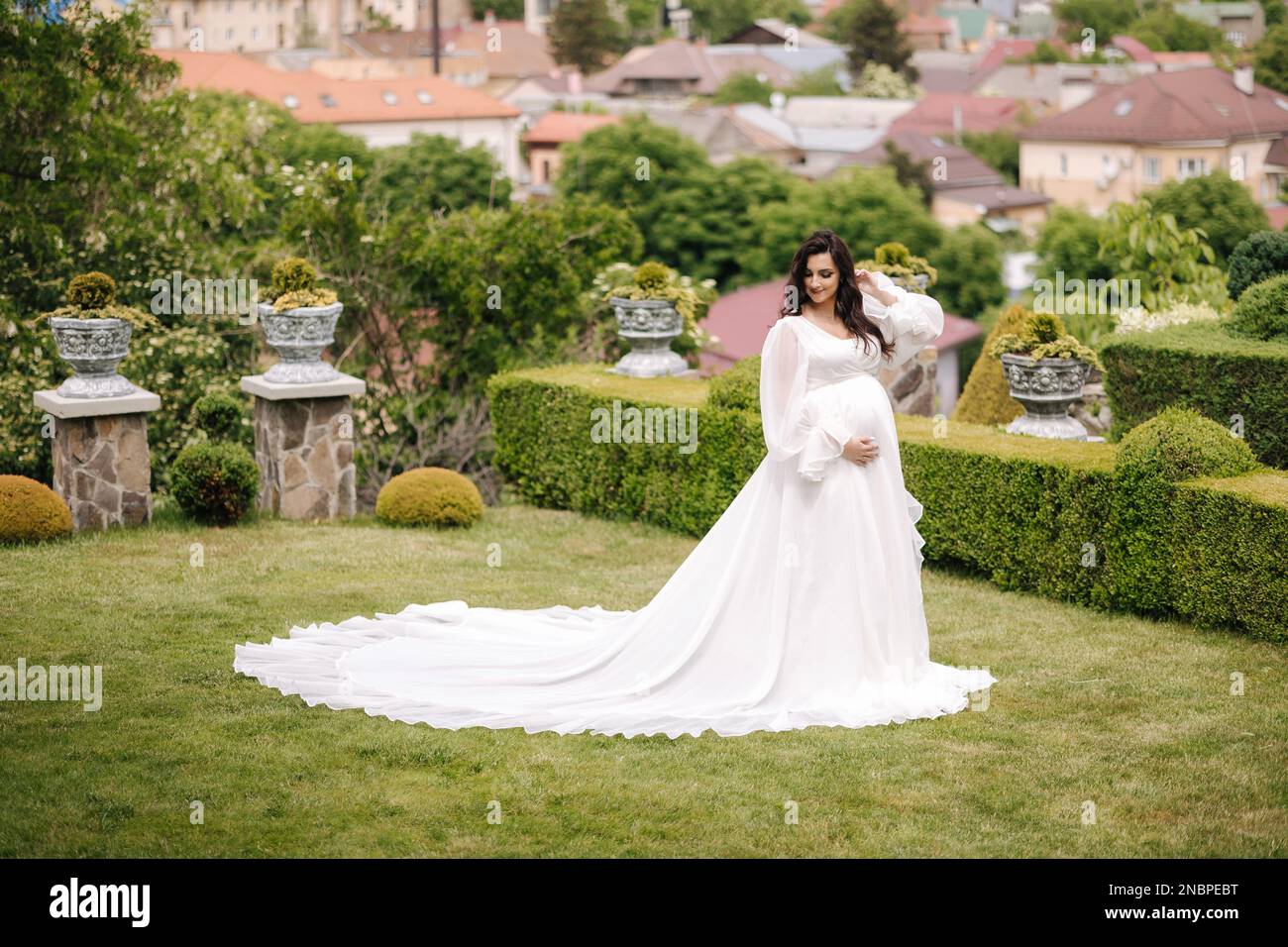 Elegant pregnant woman in beautiful white dress walking outdoors Stock ...