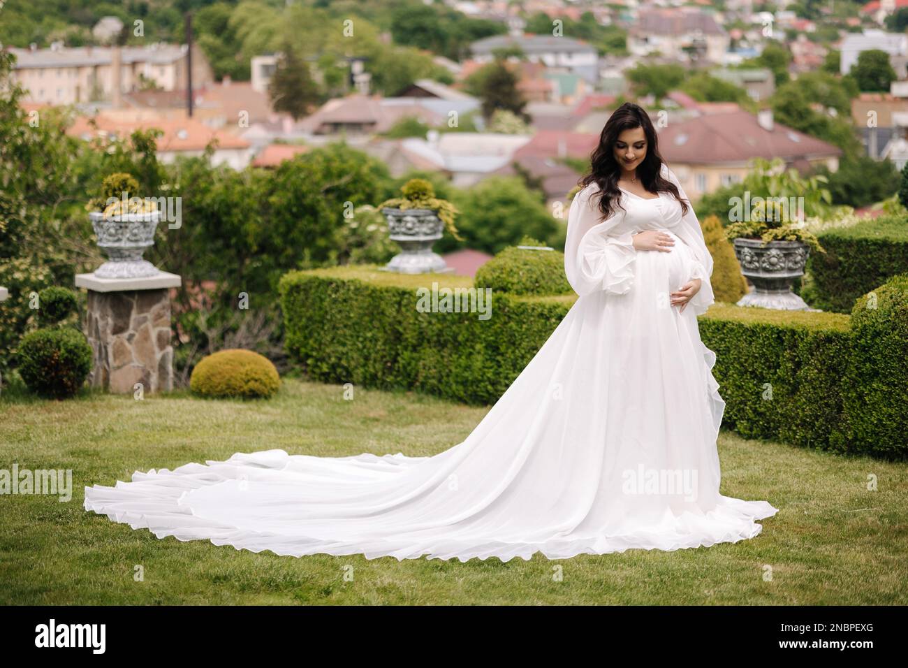 Elegant pregnant woman in beautiful white dress walking outdoors Stock ...