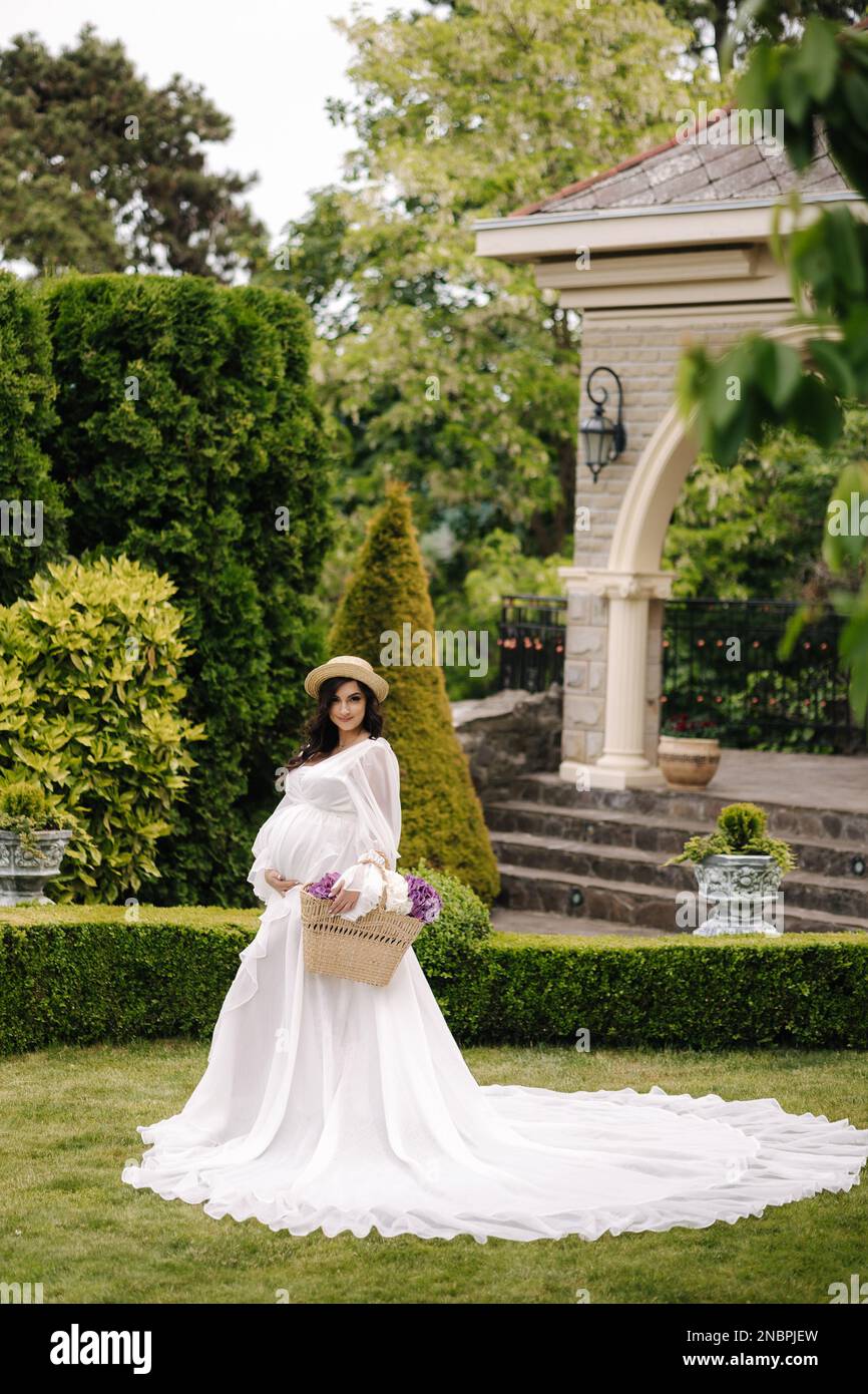 Elegant pregnant woman in beautiful white dress walking outdoors ...