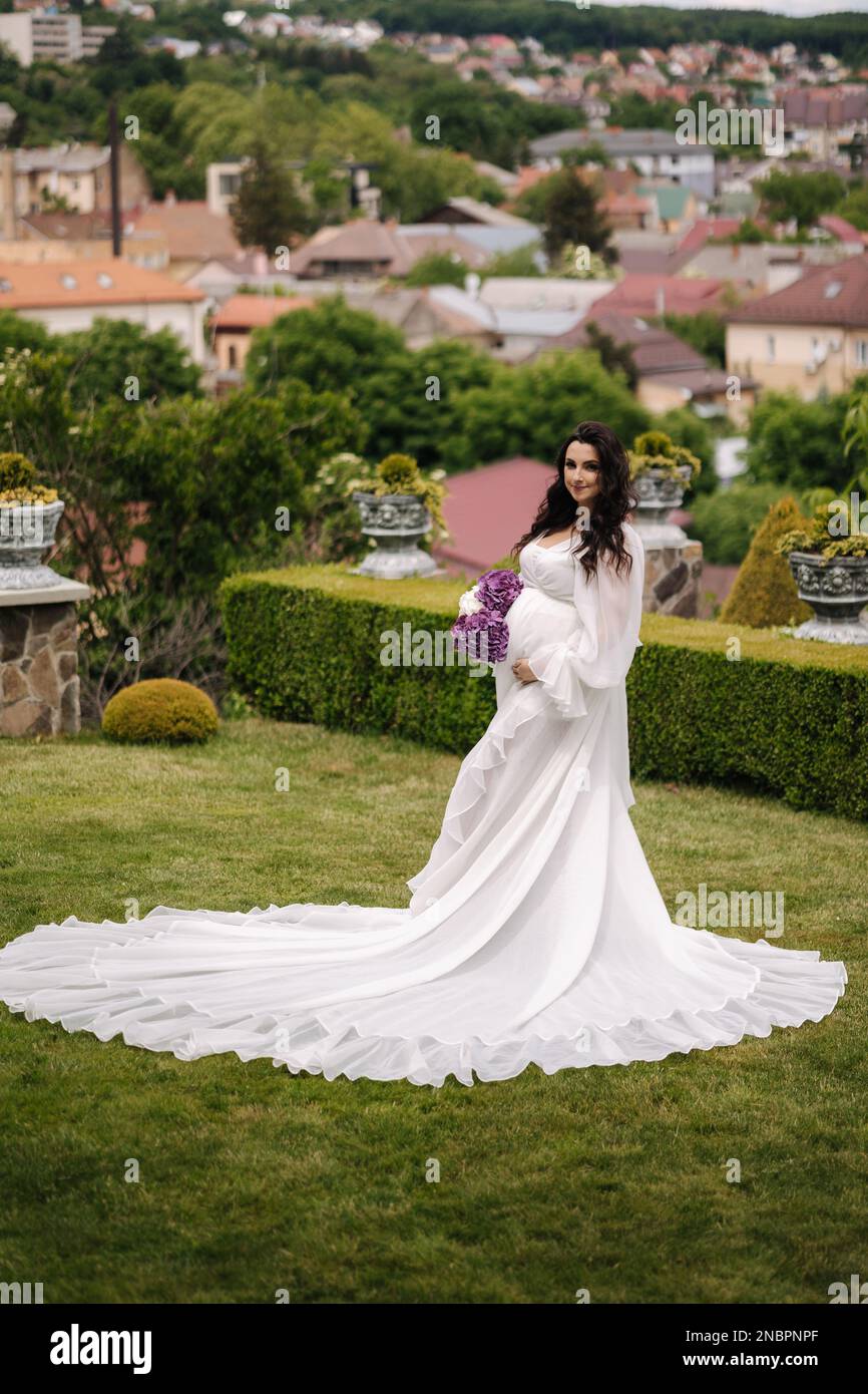 Elegant pregnant woman in beautiful white dress walking outdoors Stock ...