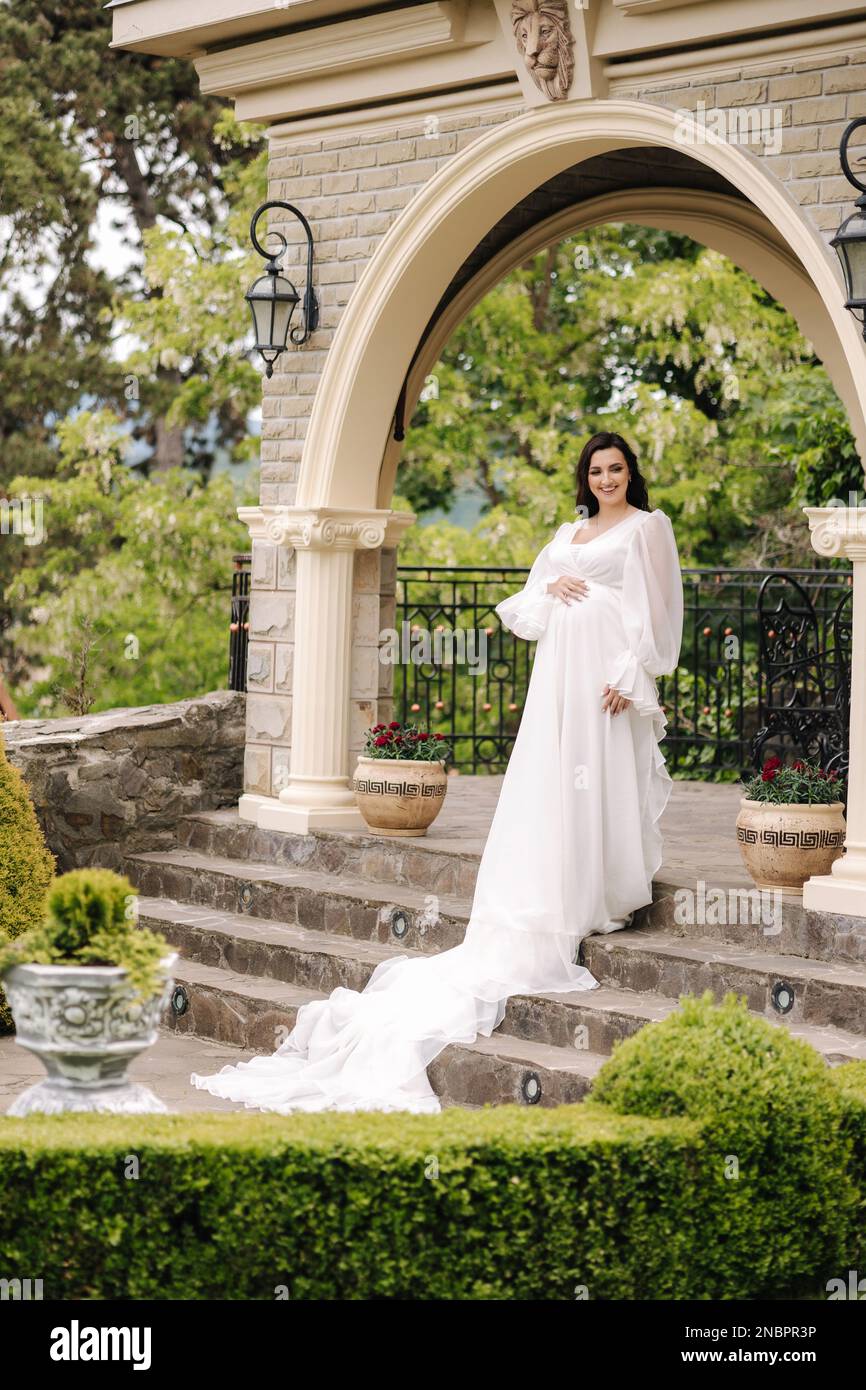 Elegant pregnant woman in beautiful white dress walking outdoors Stock ...
