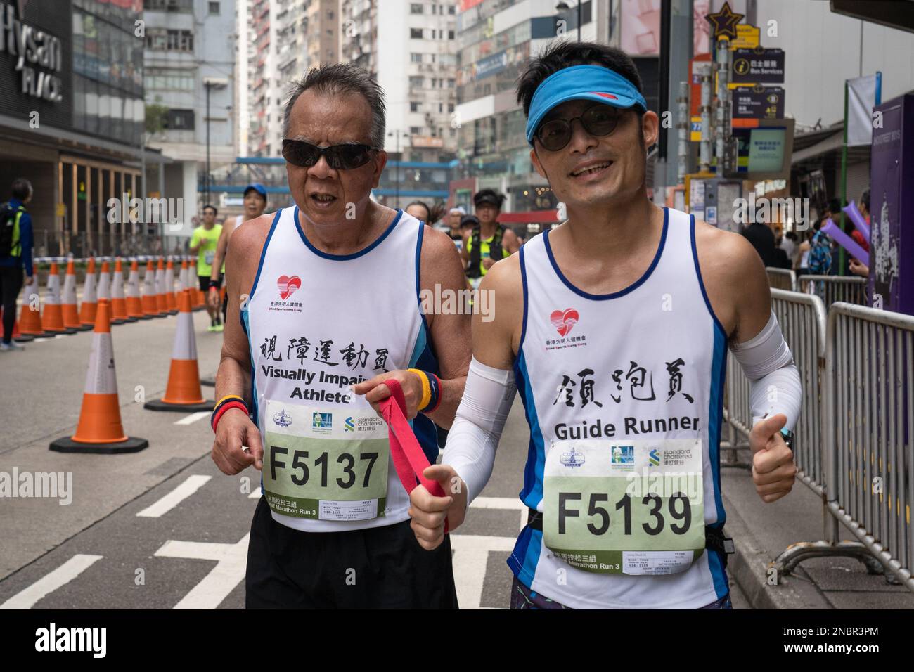 Hong Kong, China. 12th Feb, 2023. A visually impaired athlete seen holding a band as he races with a guide runner. Hong Kong Standard Chartered marathon returns as over 30,000 runners braved the humid weather to compete on a foggy day. The annual competition was suspended for about a year following the covid restriction of the city. Despite the city slowly relaxing its social distancing measures, runners must wear masks before and after the race. Credit: SOPA Images Limited/Alamy Live News Stock Photo