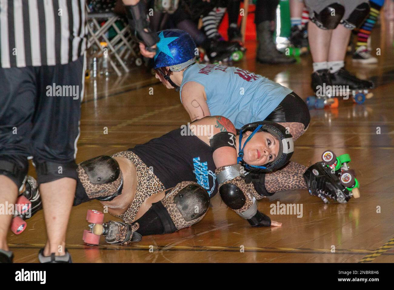Two women roller derby skaters getting up having fallen or more likely been knocked over Stock Photo
