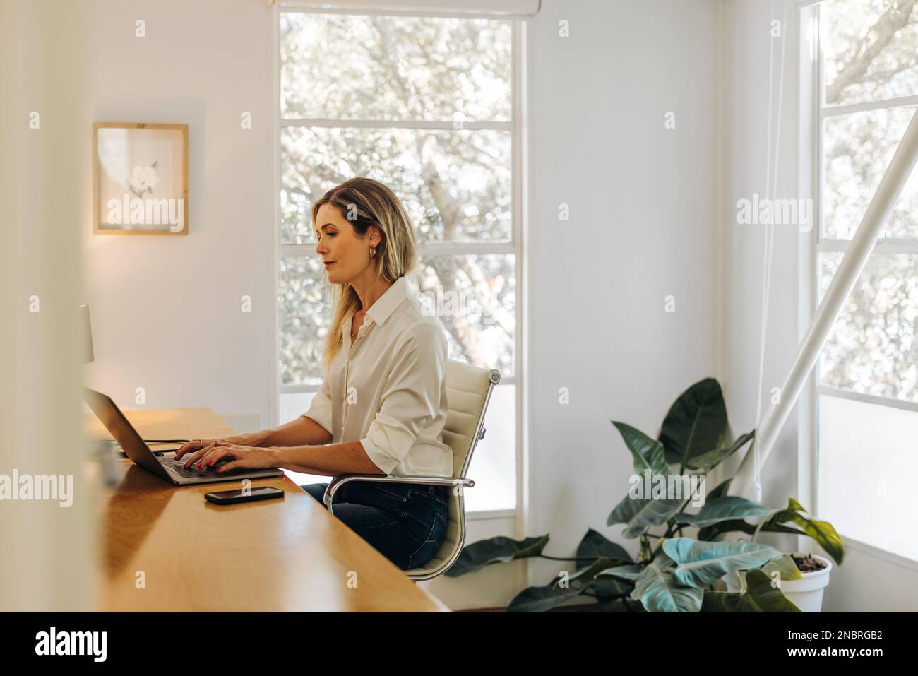 Creative businesswoman typing on a laptop while sitting in her home ...
