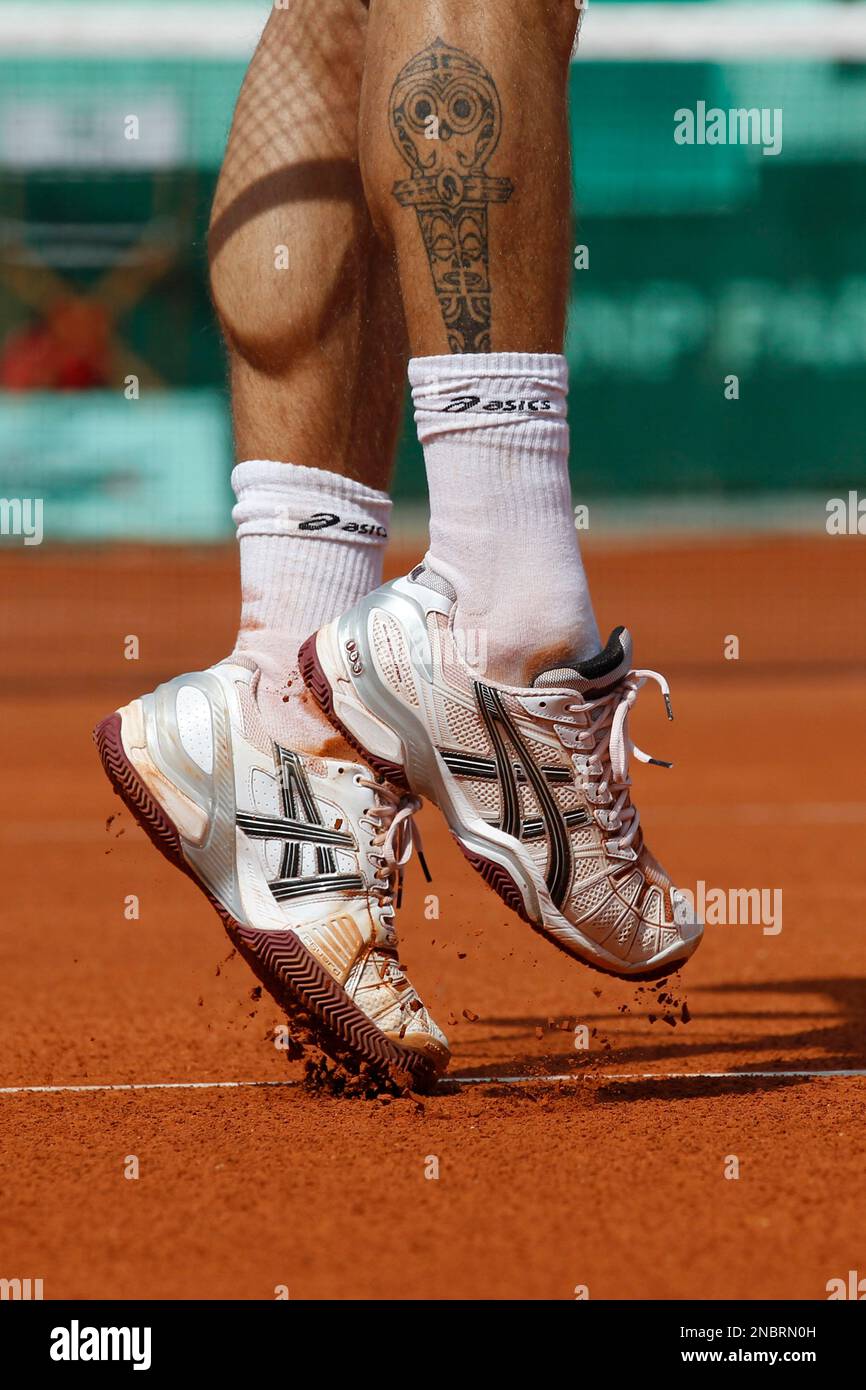 The shadow of his racket and a tattoo are seen on the legs of Augustin  Gensse of France as he serves in his first round match against Stanislas  Wawrinka of Switzerland at