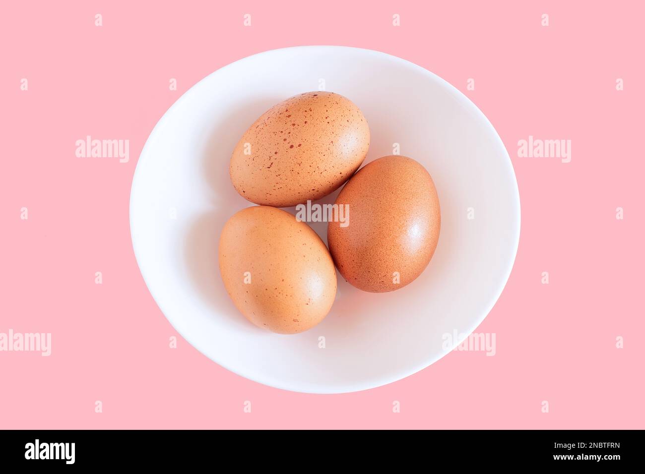 chicken egg, three chicken eggs isolated on white plate background, white plate with chicken eggs on pink background, Creative minimal concept. Stock Photo