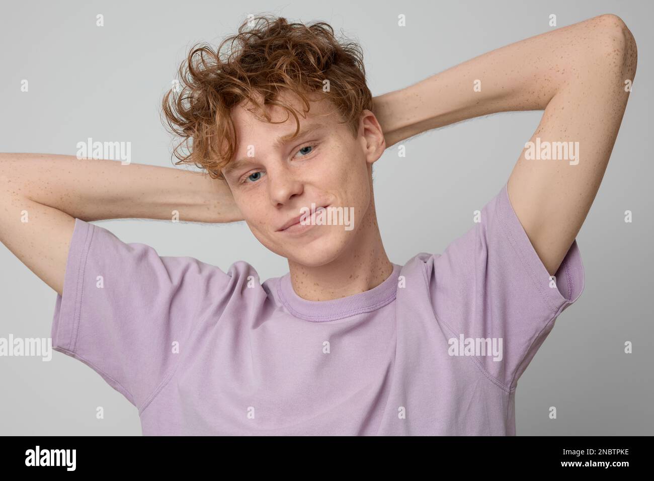 Portrait of optimistic ginger guy with freckles wearing purple tshirt